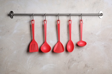 Rack with clean kitchen utensils on color wall