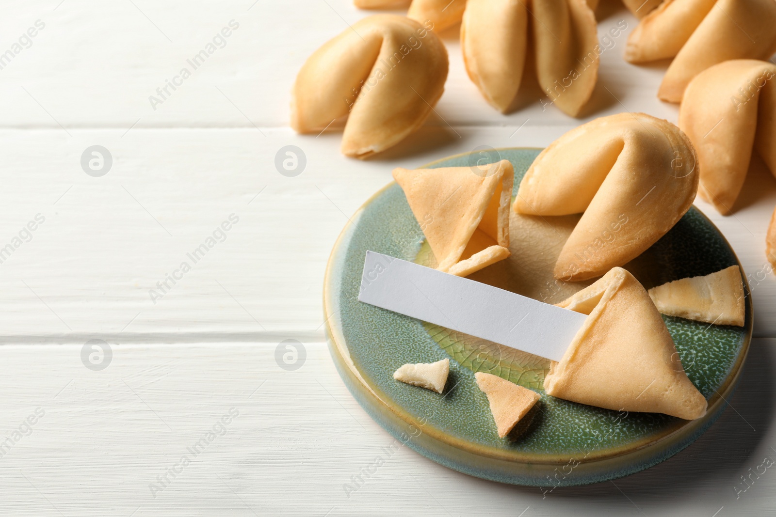 Photo of Tasty fortune cookies and paper with prediction on white wooden table, space for text