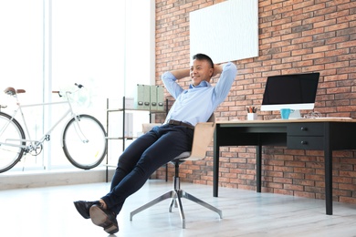 Happy young businessman relaxing in office. Enjoying peaceful moment