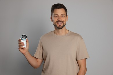 Photo of Handsome man holding fabric shaver on light grey background