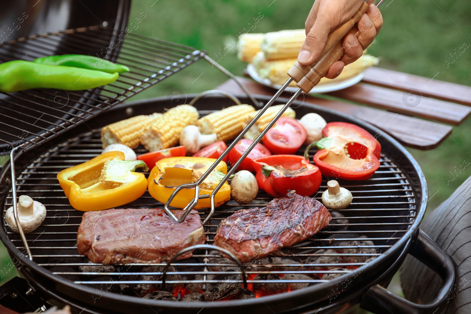 Photo of Man cooking food on barbecue grill outdoors, closeup