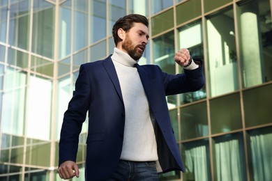 Photo of Businessman checking time on watch near building. Being late concept