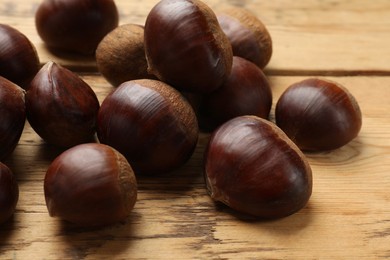 Photo of Sweet fresh edible chestnuts on wooden table, closeup