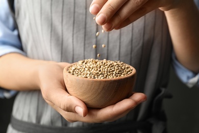 Woman holding bowl with organic hemp seeds, closeup