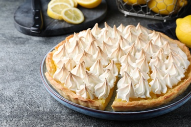 Photo of Cut delicious lemon meringue pie on grey table, closeup