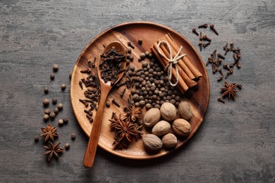 Photo of Different spices and nuts on gray textured table, top view