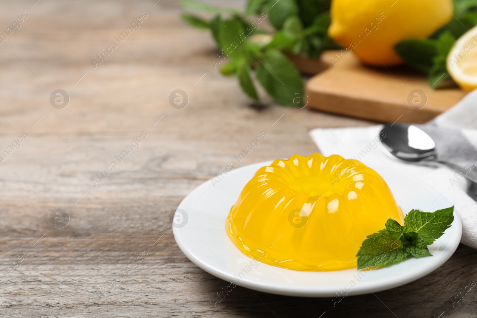 Photo of Delicious fresh yellow jelly with mint on wooden table. Space for text