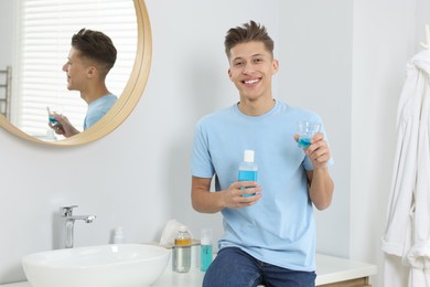 Photo of Young man with mouthwash in bathroom. Oral hygiene