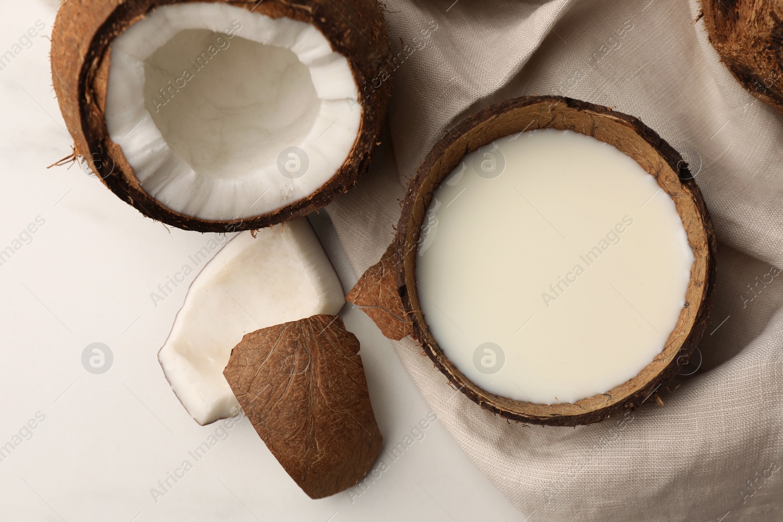 Photo of Delicious vegan milk in coconut and pieces of ripe fruit on white table, flat lay