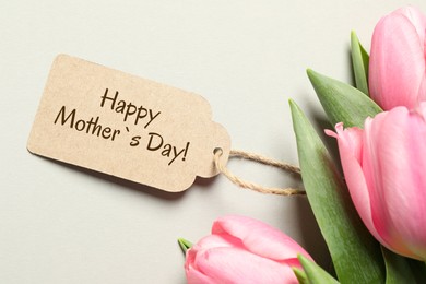 Happy Mother's Day greeting label and beautiful tulip flowers on beige background