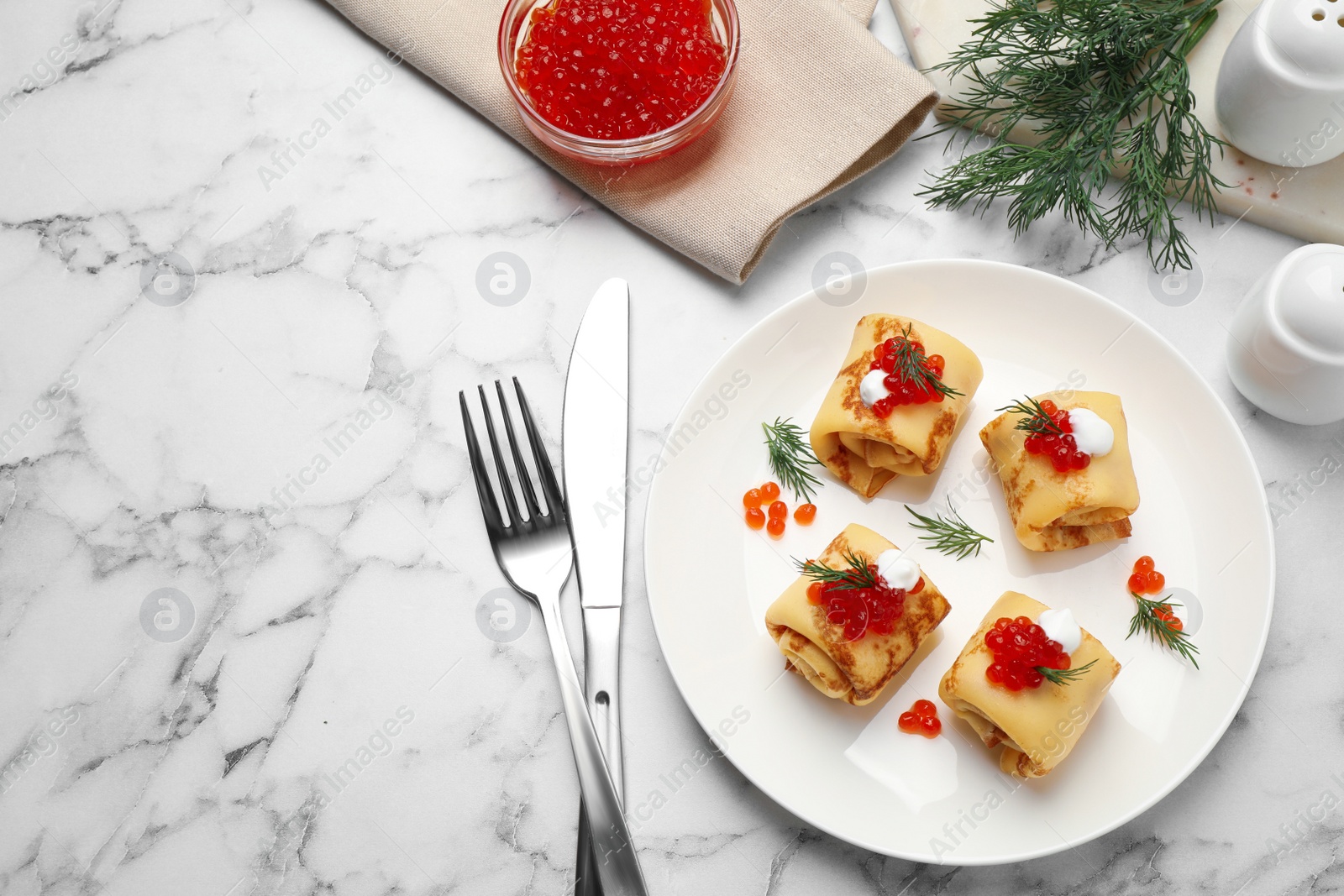 Photo of Delicious thin pancakes with red caviar on white marble table, flat lay. Space for text