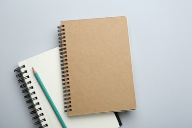 Notebooks and pencil on light grey background, top view
