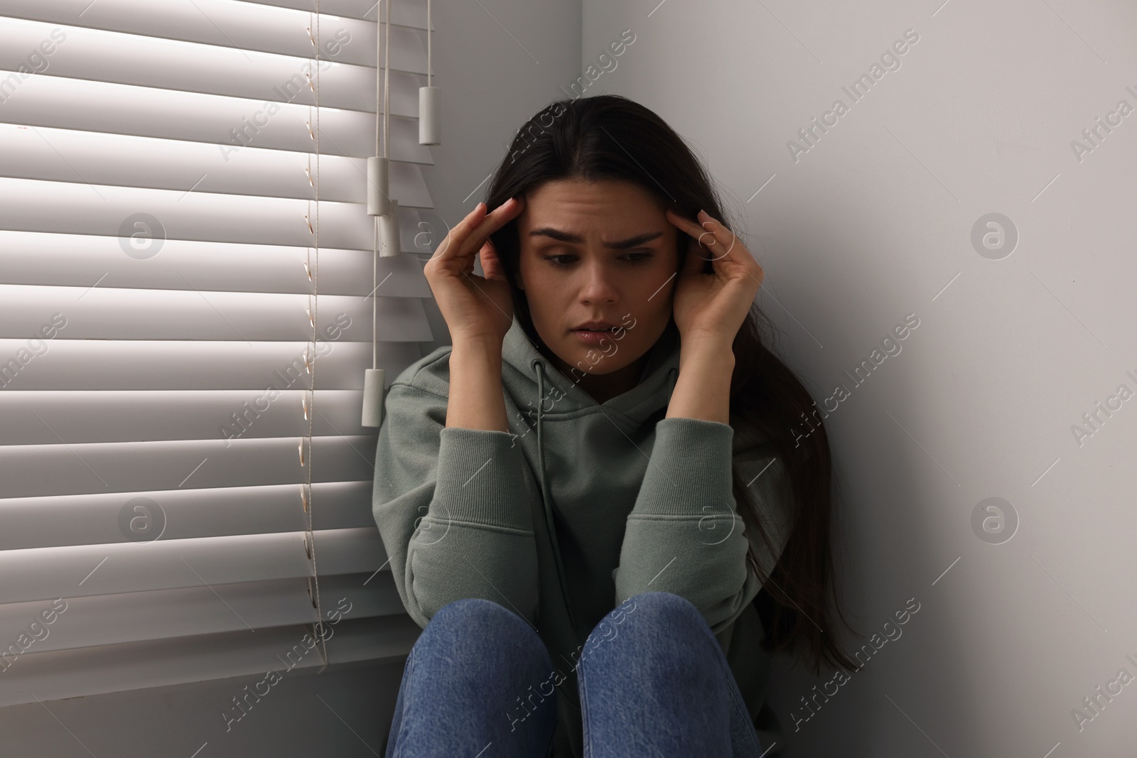 Photo of Sadness. Unhappy woman near window at home