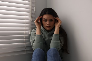 Sadness. Unhappy woman near window at home