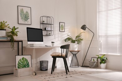 Photo of Comfortable workplace with modern computer and houseplants in room. Interior design