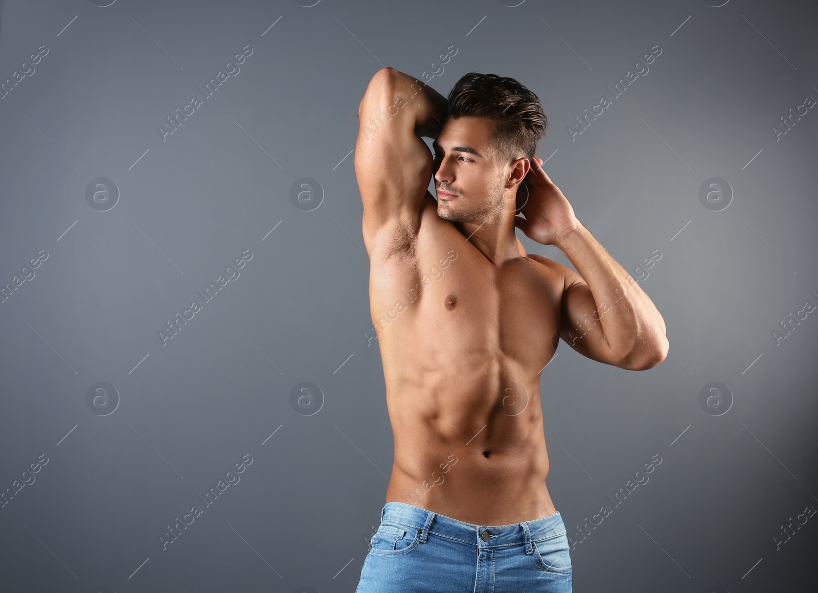 Photo of Shirtless young man in stylish jeans on grey background