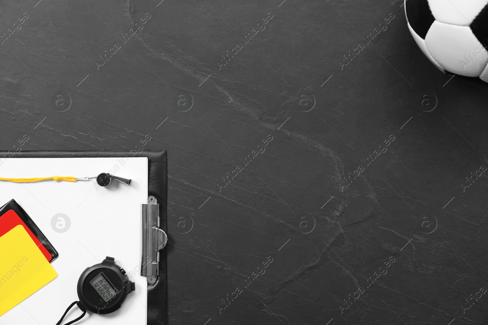 Photo of Soccer ball and different referee equipment on black table, top view. Space for text