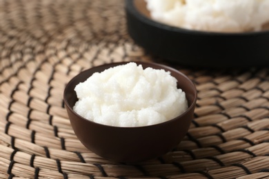 Photo of Shea butter in bowl on wicker mat, closeup