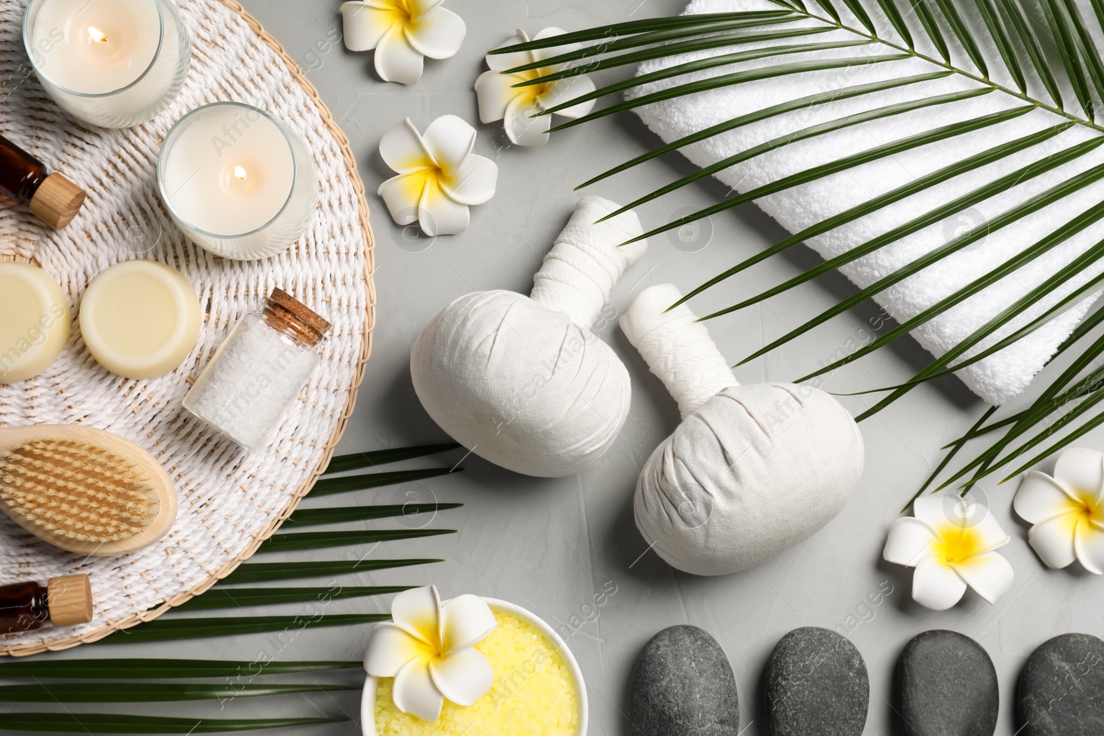 Photo of Spa bags, stones and orchid flowers on light gray table, flat lay