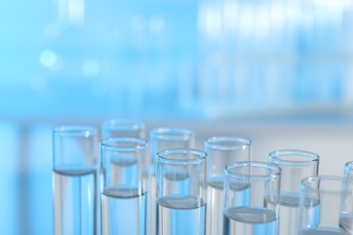 Photo of Many glass test tubes on light blue background, closeup