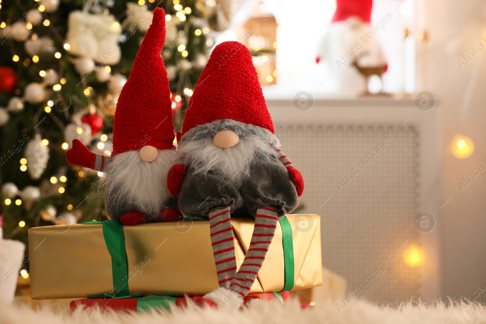 Photo of Cute Christmas gnomes and gift boxes on carpet in room