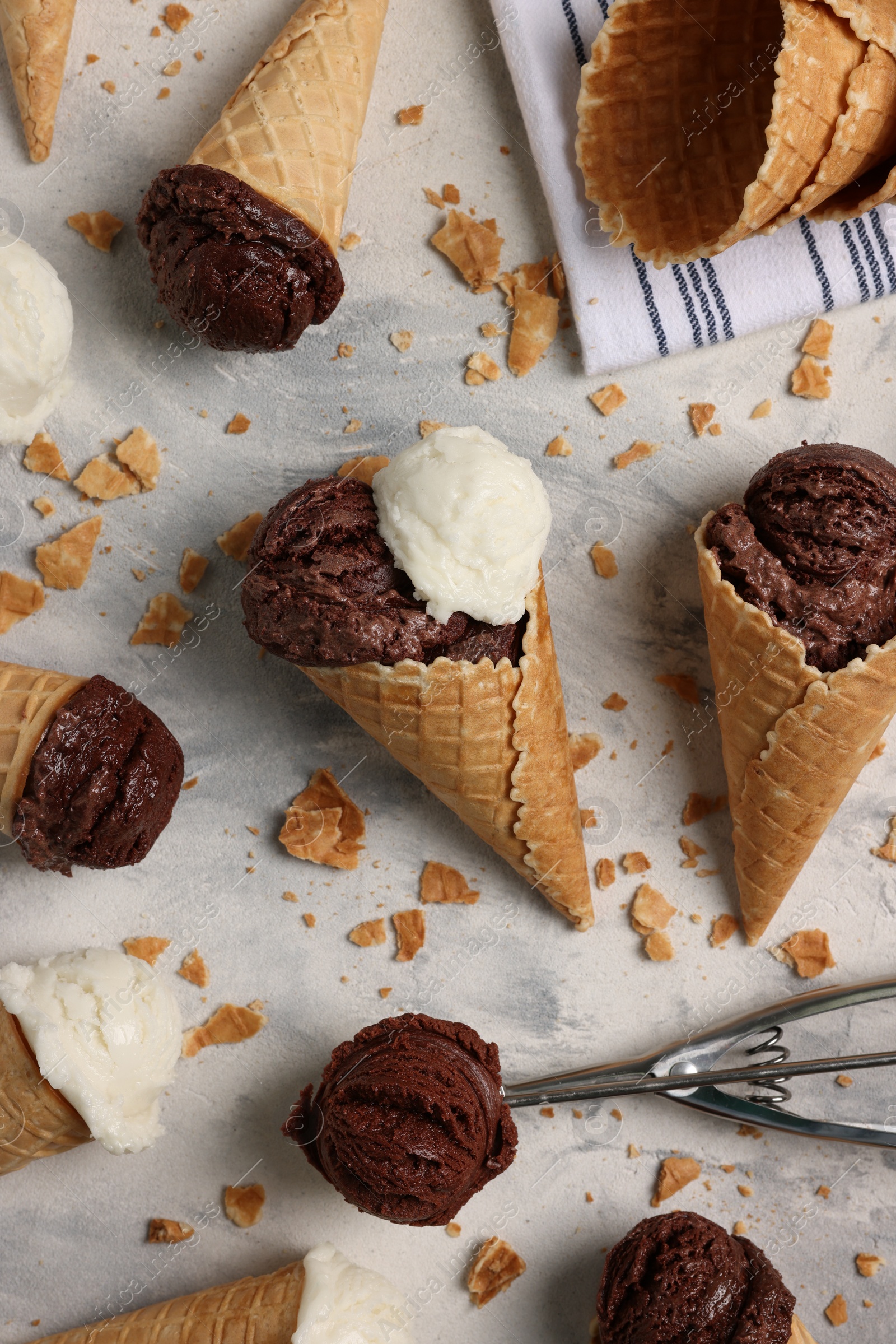 Photo of Flat lay composition with tasty ice cream scoops in waffle cones on light textured table