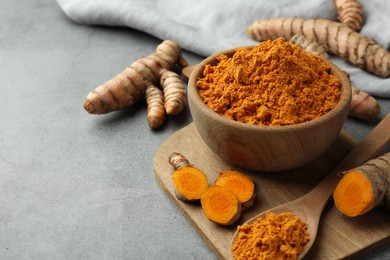 Photo of Aromatic turmeric powder and cut roots on grey table. Space for text