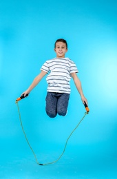 Photo of Full length portrait of boy jumping rope on color background