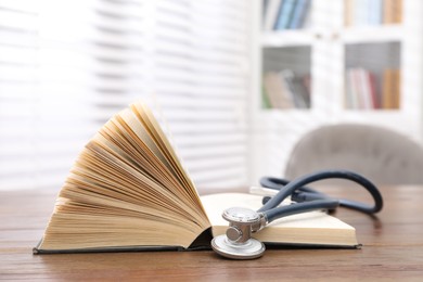 Photo of Book and stethoscope on wooden table indoors, space for text. Medical education