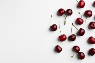Many sweet ripe cherries on white background, flat lay. Space for text