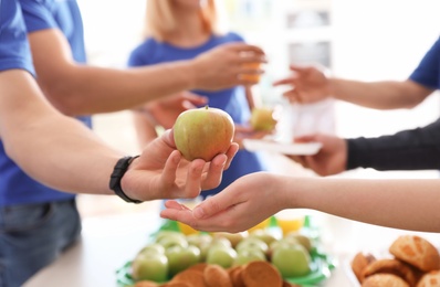 Photo of Volunteer giving apple to poor person, closeup