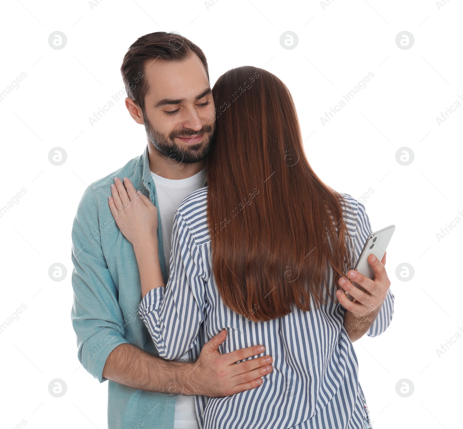 Photo of Man interested in smartphone while hugging his girlfriend on white background. Relationship problems