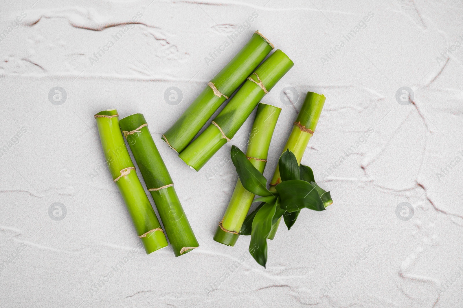 Photo of Pieces of beautiful green bamboo stems on white textured background, flat lay