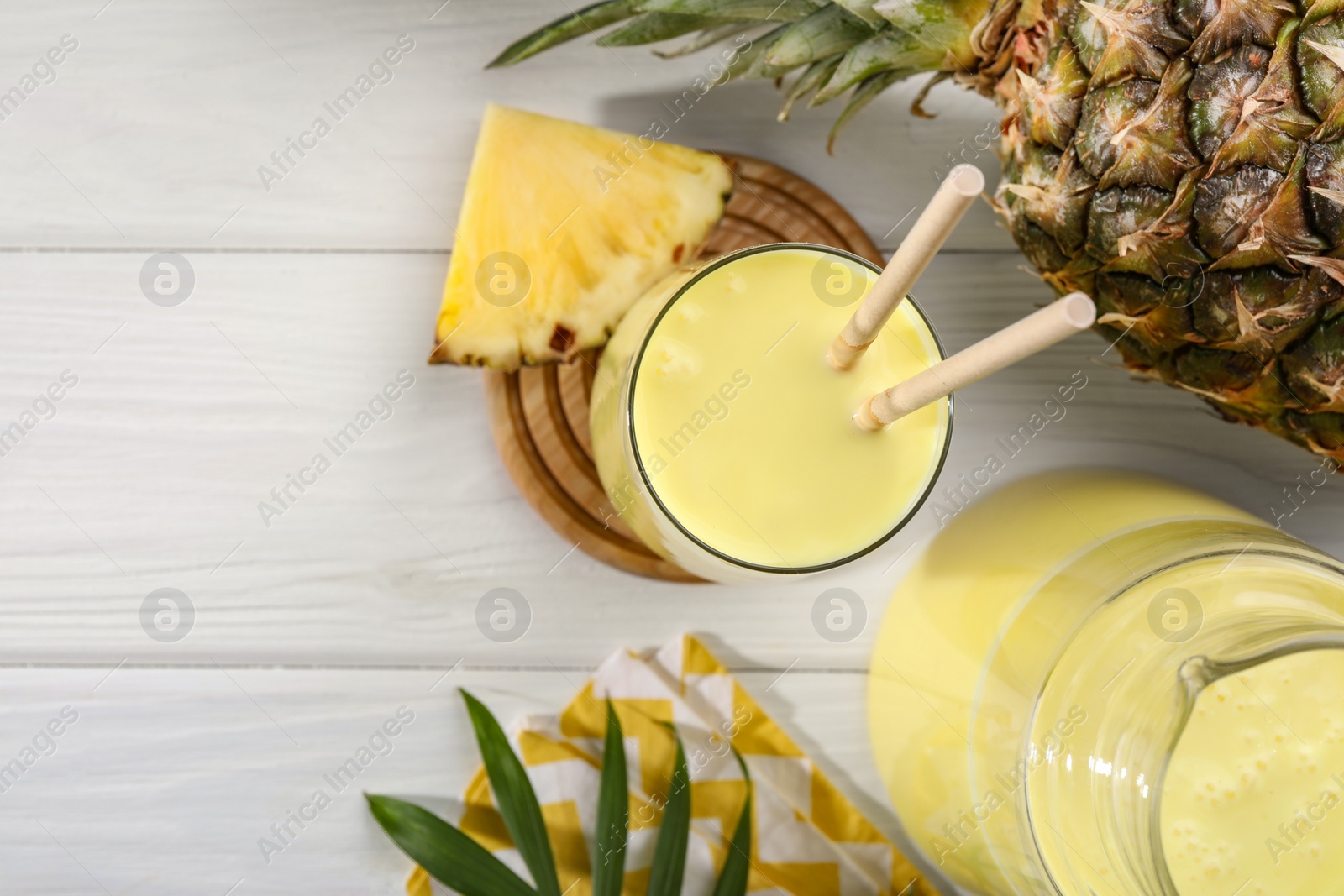 Photo of Tasty pineapple smoothie and fruit on white wooden table, flat lay. Space for text