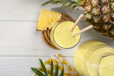 Photo of Tasty pineapple smoothie and fruit on white wooden table, flat lay. Space for text