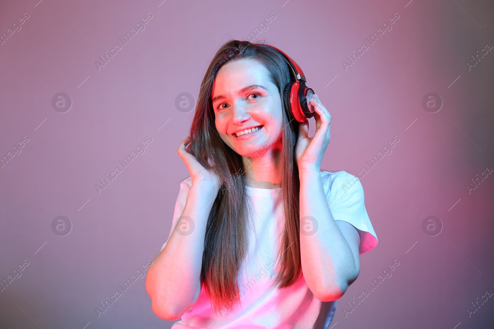 Photo of Portrait of beautiful woman with headphones in neon lights on color background