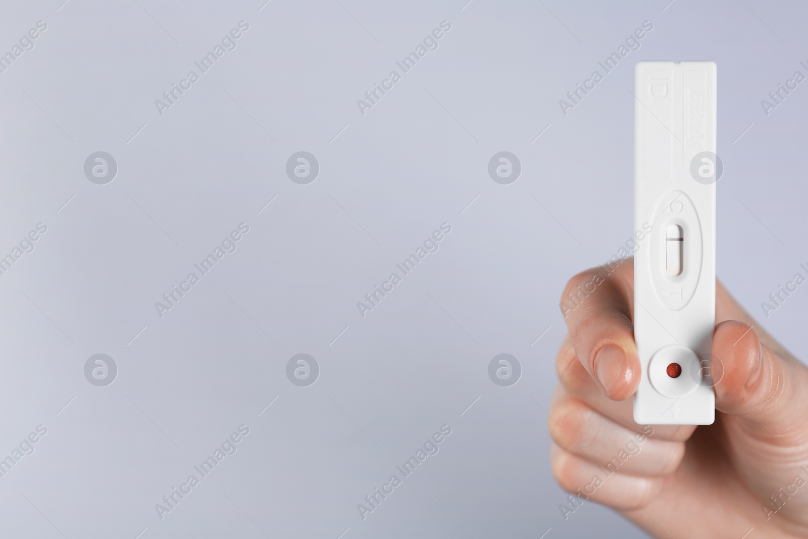 Photo of Woman holding disposable express test on light background, closeup. Space for text