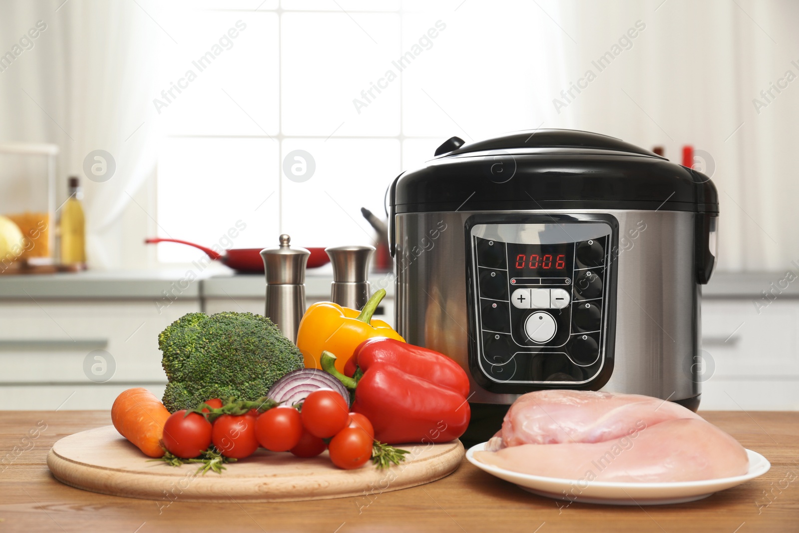 Photo of Modern multi cooker and ingredients on wooden table in kitchen