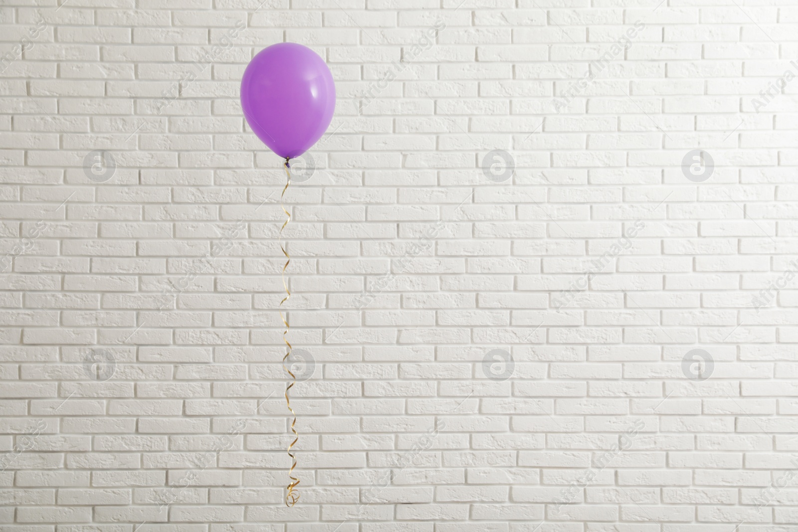 Photo of Bright balloon near brick wall, space for text. Celebration time