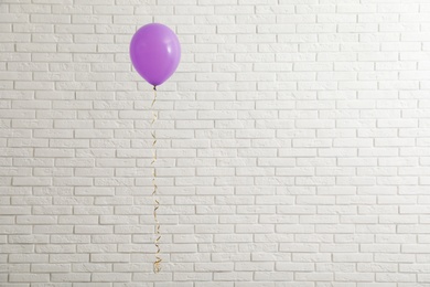 Bright balloon near brick wall, space for text. Celebration time