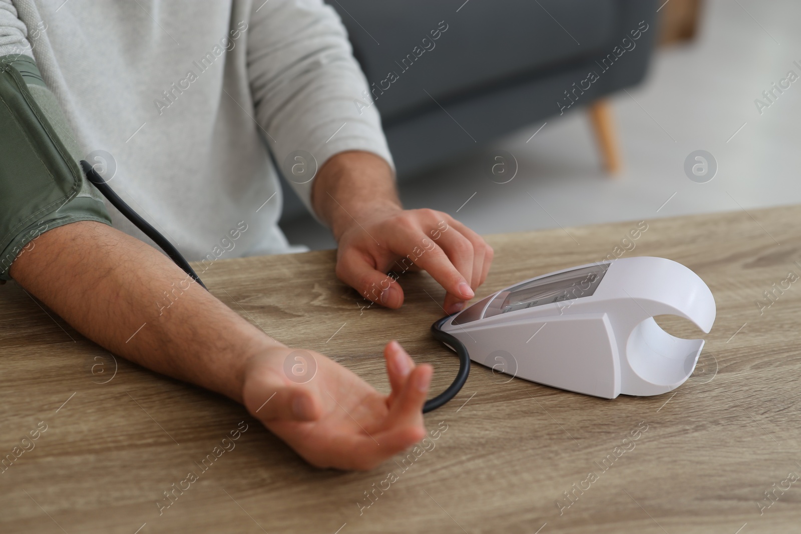 Photo of Man checking blood pressure at wooden table indoors, closeup