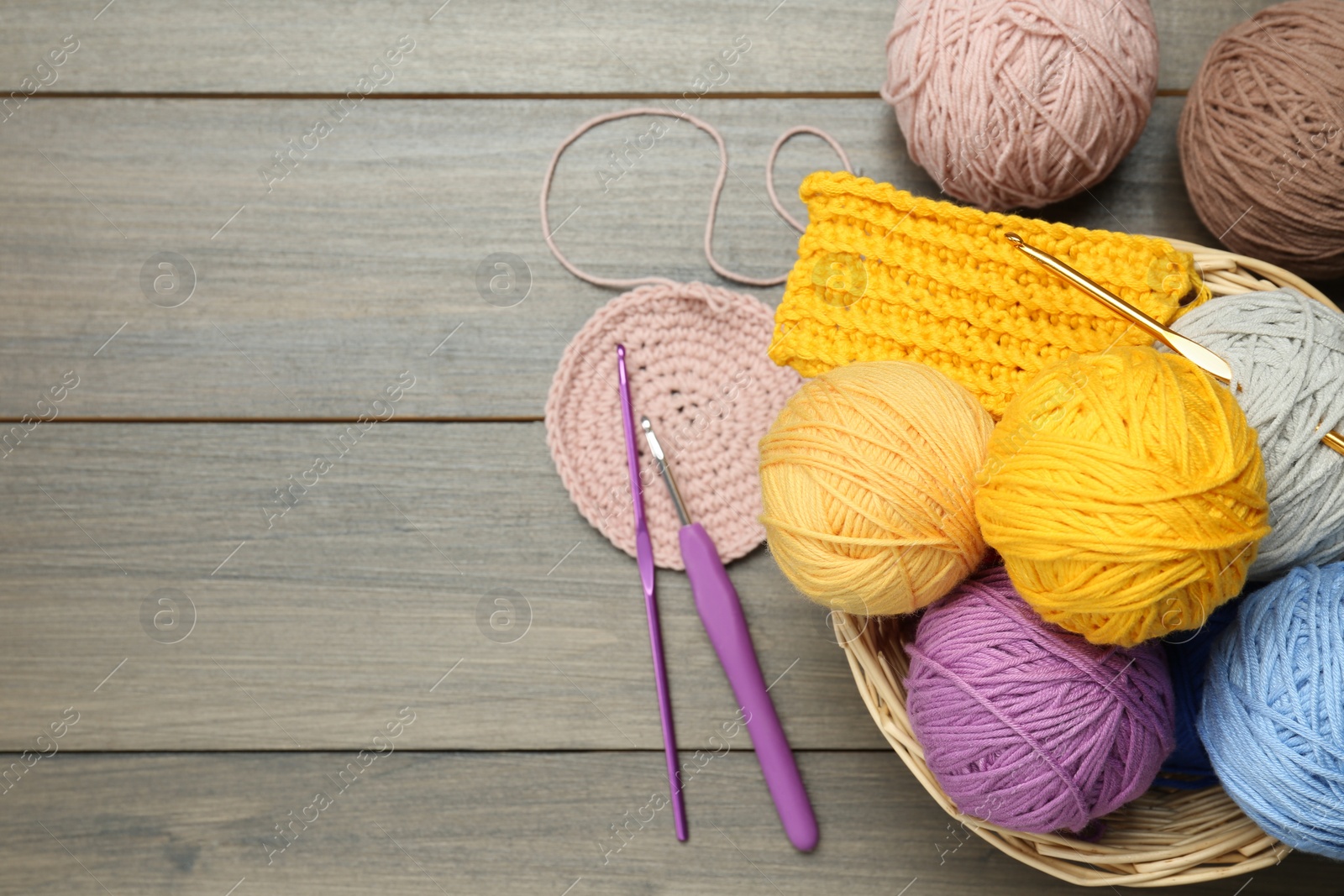 Photo of Clews, knitting and crochet hooks on wooden table, flat lay. Space for text