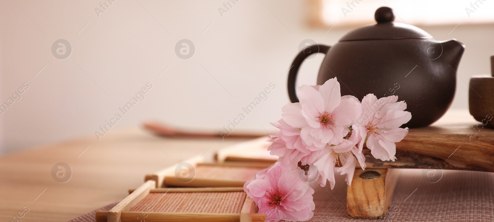 Image of Pot, sakura flowers and bamboo coasters for traditional tea ceremony on table. Banner design