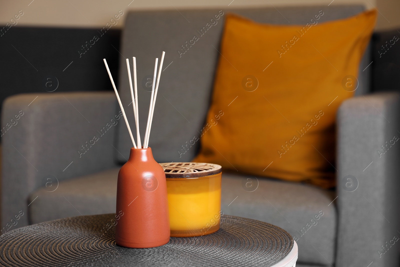 Photo of Aromatic reed air freshener and scented candle on table indoors