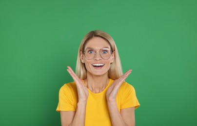 Photo of Portrait of emotional woman in stylish glasses on green background