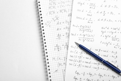 Photo of Sheets of paper with different mathematical formulas and pen on white table, top view. Space for text