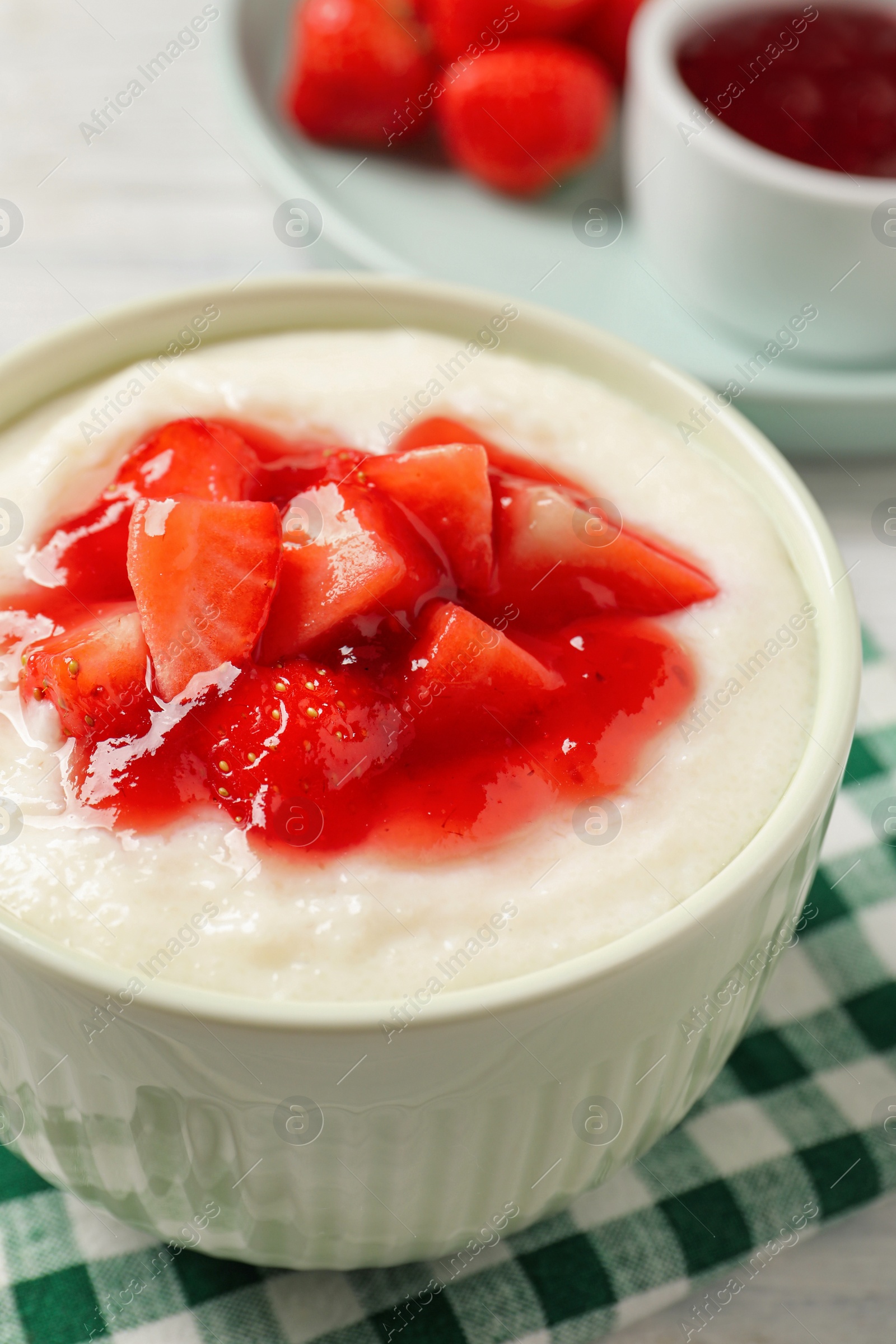 Photo of Delicious semolina pudding with strawberries and jam on white table