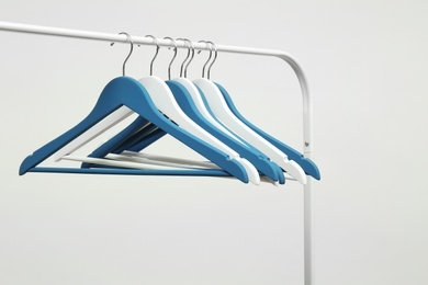 Photo of Empty clothes hangers on metal rack against light background