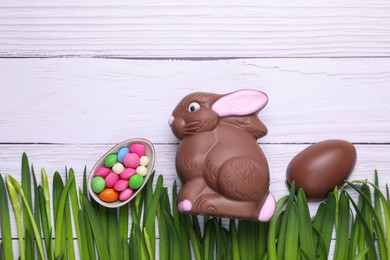 Photo of Easter celebration. Flat lay composition with cute chocolate bunny and tasty sweets on white wooden table