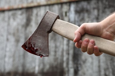 Photo of Man holding bloody axe outdoors, closeup view